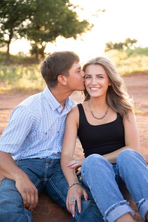 Romantic couple in casual denim and plaid sitting together outdoors during golden hour sunset.