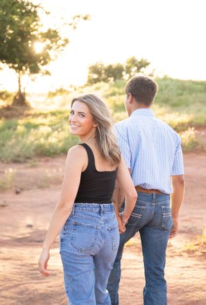 A couple in casual attire walking together at sunset on a desert trail with warm golden lighting.