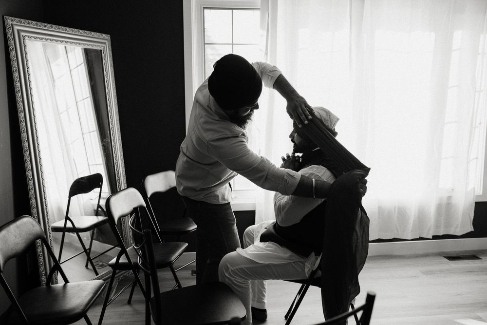 Black and white photo of a person getting their hair styled before a wedding ceremony.