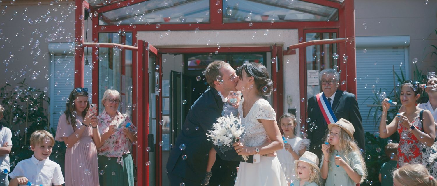 Wedding party gathers outside a rustic red barn venue during a countryside celebration.