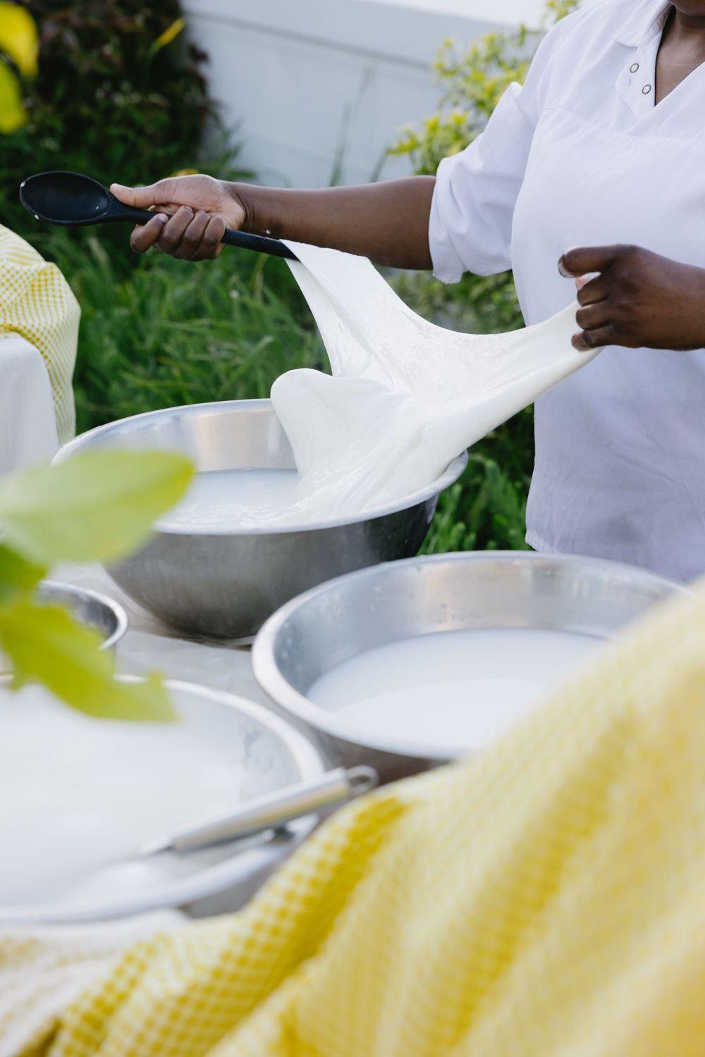 White plates and yellow checkered linens being set up for an outdoor dining event.