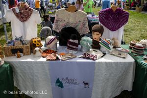 Vendor tables with crafts and merchandise displayed at outdoor market.