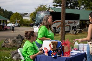 Outdoor event setup with tables and tents displaying various vendor booths at a festival.