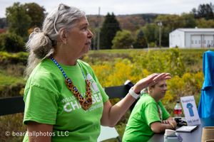 Vendors in bright green shirts setting up displays at outdoor tables under a covered area.