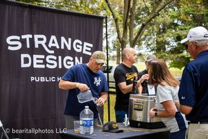 Black banner with 'Strange Design' text displayed at an outdoor event.