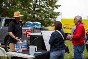 People gathered around pickup trucks at an outdoor festival event.