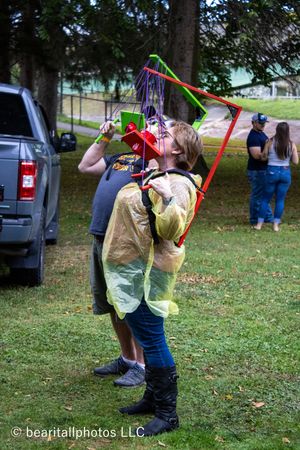 Person in yellow rain poncho playing with colorful streamers at outdoor festival.