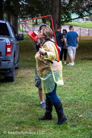 Festival attendee in yellow poncho dancing with red streamers on grassy lawn.