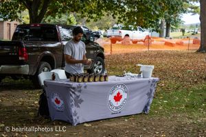 Row of vendor booths with white table coverings at an outdoor festival.