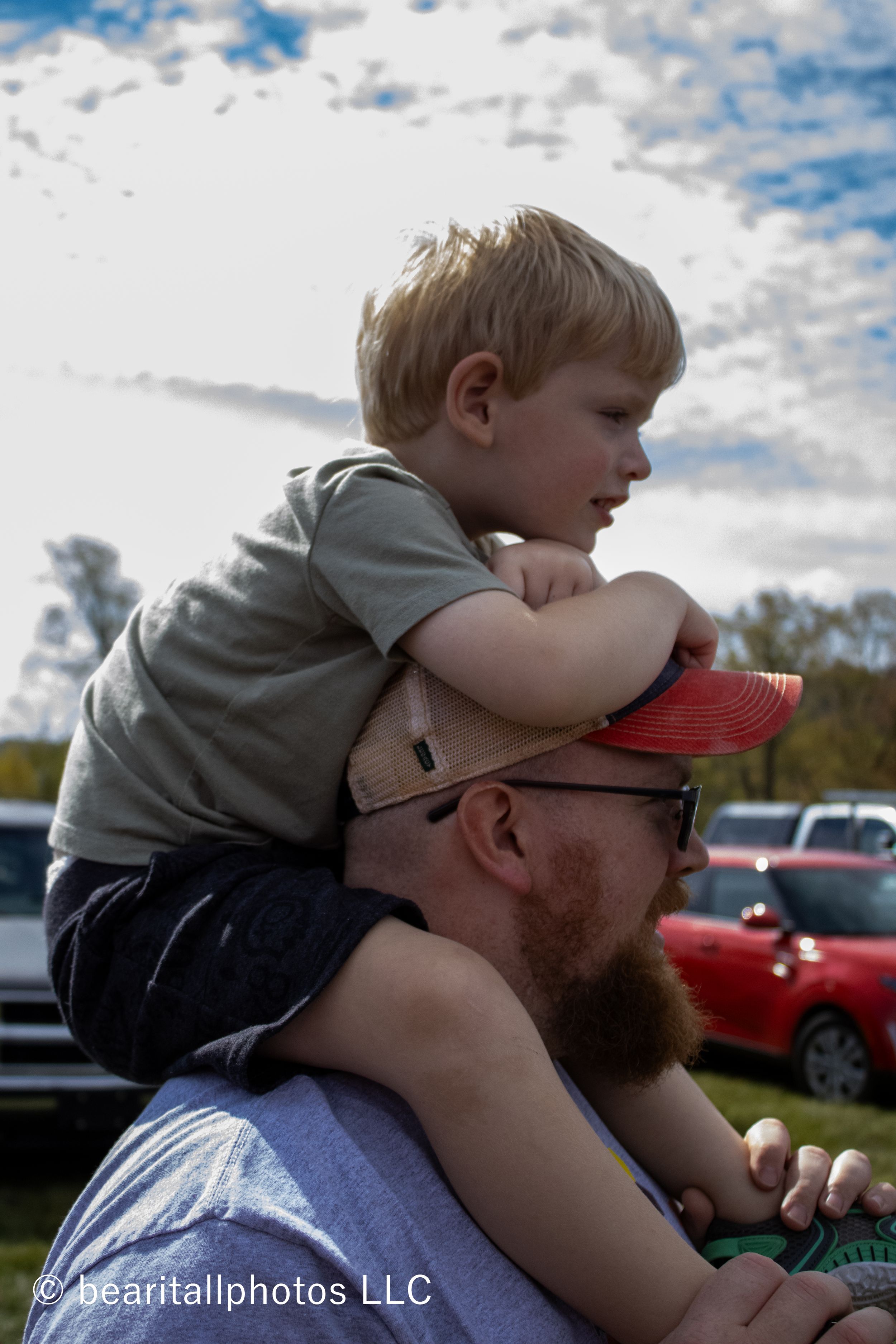 Parent and child sharing a playful moment outdoors on a cloudy autumn day.