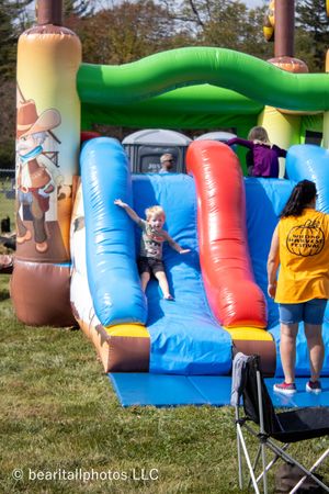 Colorful inflatable bounce house obstacle course with blue, red and yellow sections set up outdoors on grass.