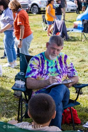 People relaxing in camping chairs at an outdoor festival on a sunny day.