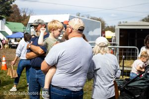 Crowd of people gathered at an outdoor event with tents visible in background.