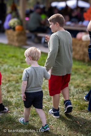 Children walking on grass wearing casual summer clothing at an outdoor event.