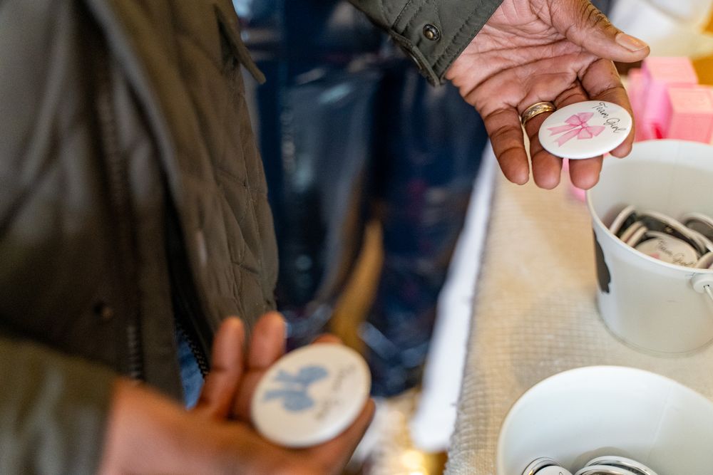 Hands examining vintage decorative pins and coins at an antique market stall with collectibles on display.