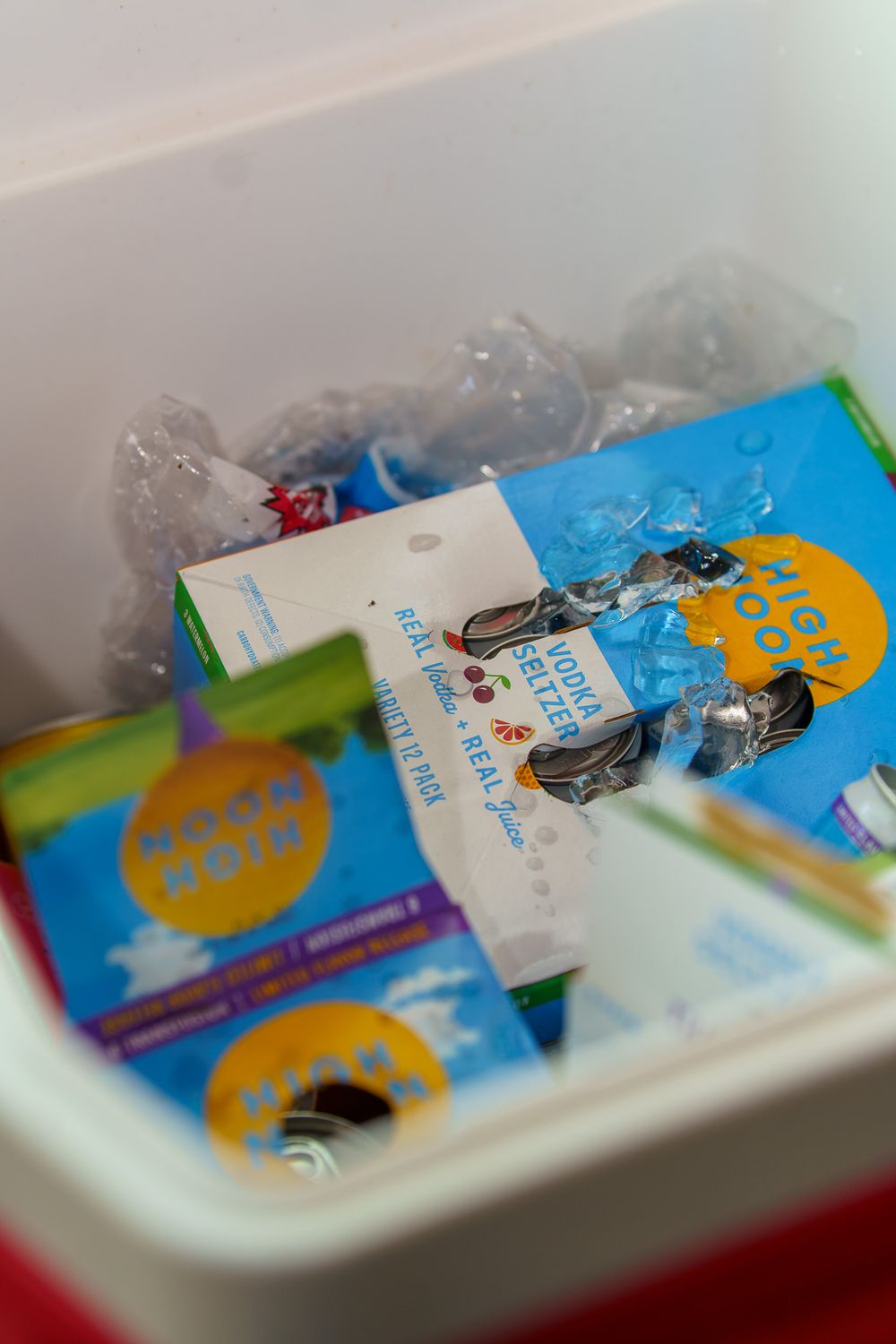 A cooler filled with ice, Mojo Mojo drink boxes, and various snacks and beverages packed together.