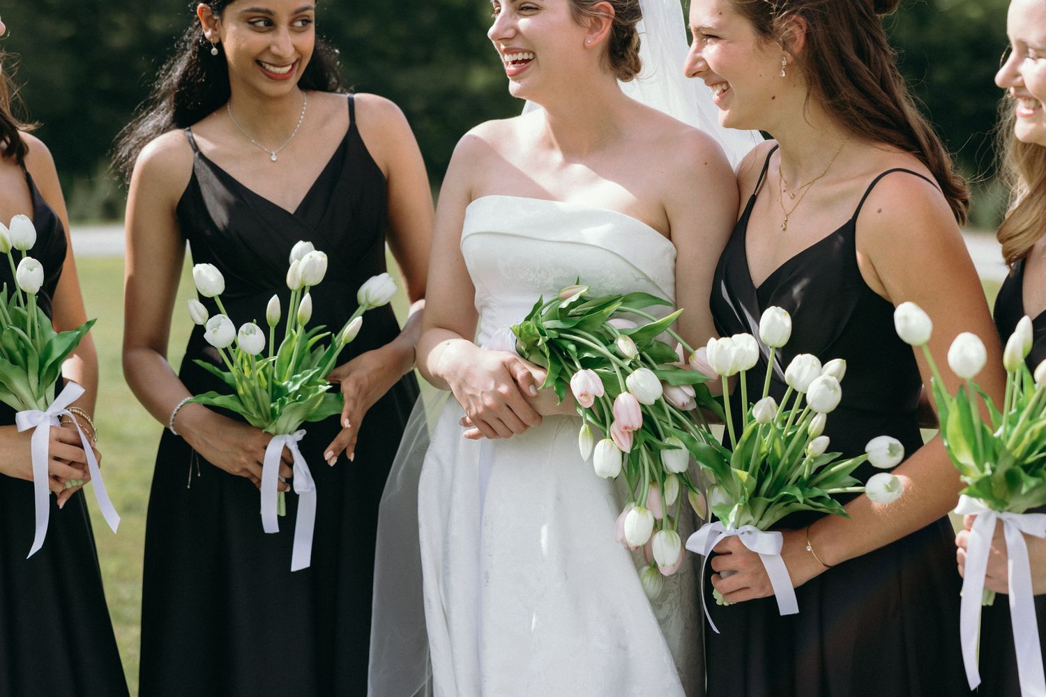 A couple in wedding attire walks hand in hand through a sunlit garden with lush trees and manicured shrubs. East Coast Luxury wedding photos