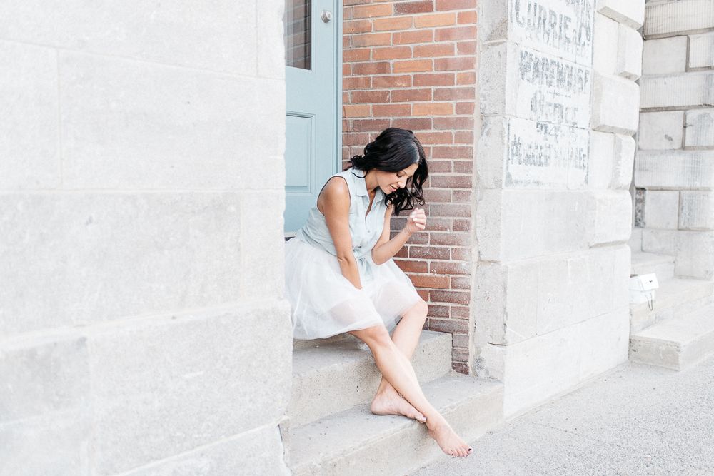 Portrait lifestyle en extérieur urbain, personne assise près d’un mur de pierre, lumière naturelle douce