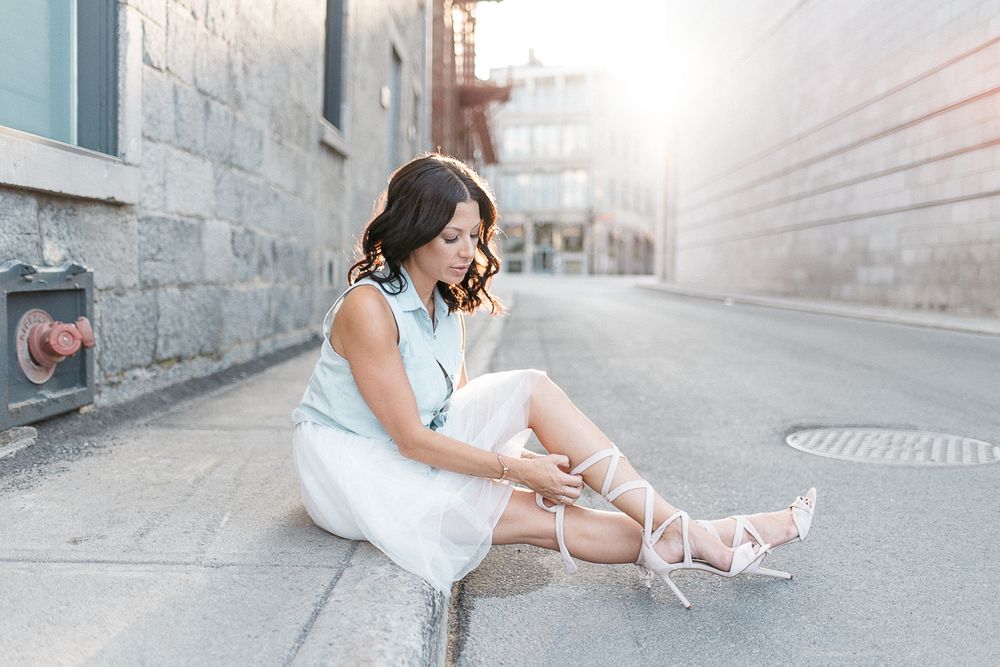 Portrait urbain en extérieur, personne assise au sol avec robe blanche et architecture de béton
