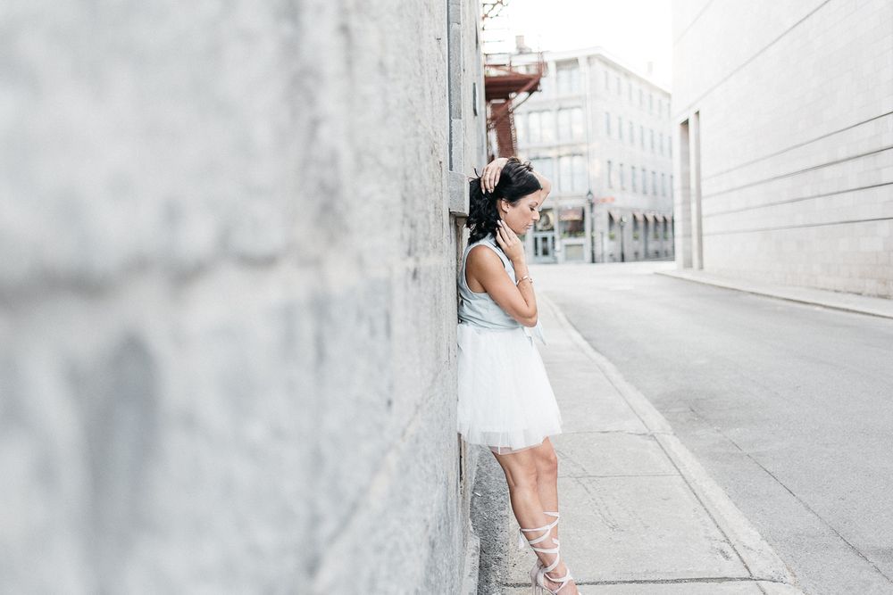 Séance portrait en lumière naturelle, personne en robe blanche près d’un mur de béton