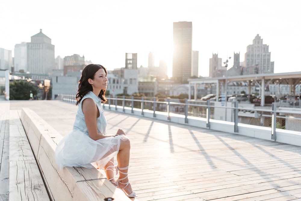 Photo portrait lifestyle en extérieur, banc en bois et skyline urbaine en arrière-plan