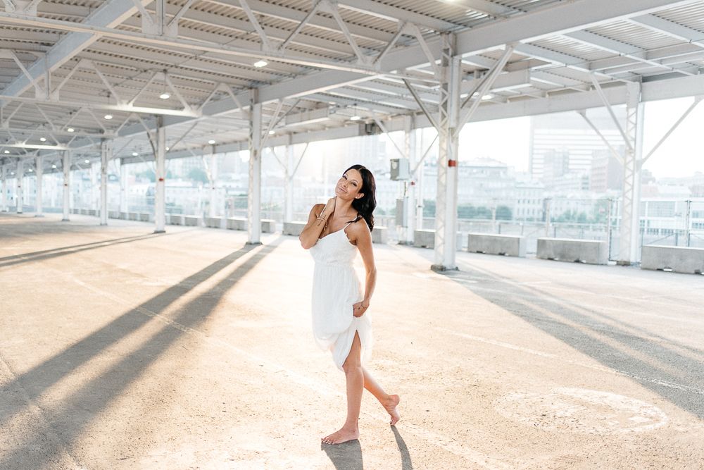 Portrait lifestyle en extérieur urbain, personne en robe blanche sous une structure vitrée