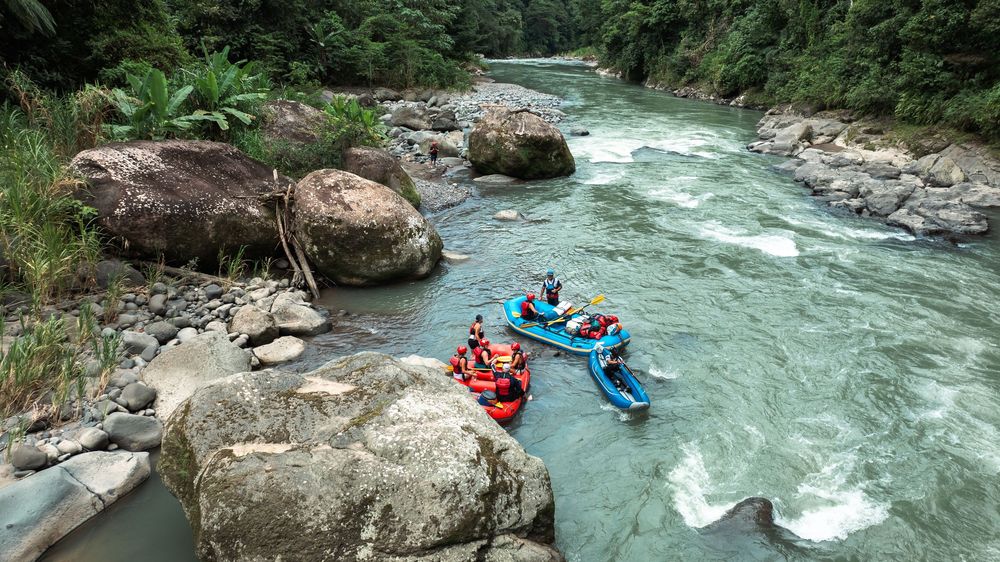 Scenic river with turquoise waters flowing between large boulders and forested banks.