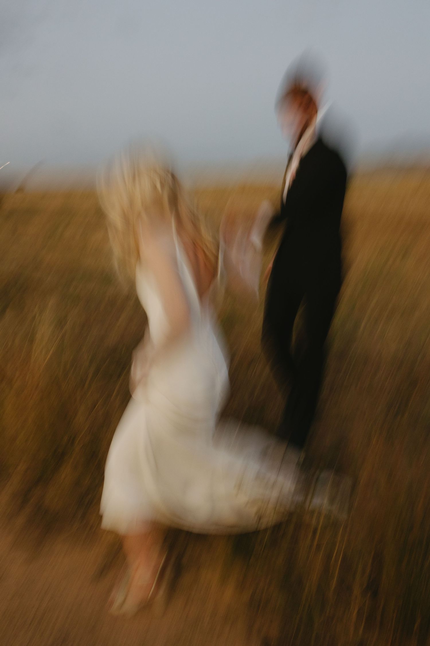 Motion blur sequence of two figures dancing in a golden wheat field at sunset.