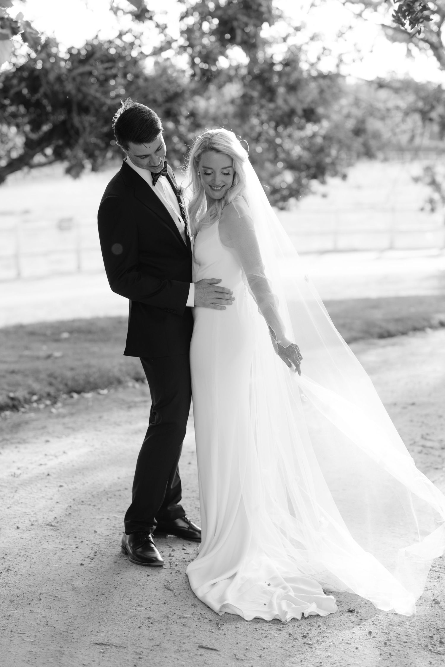 Black and white wedding photos show a romantic moment between a couple in formal attire outdoors.