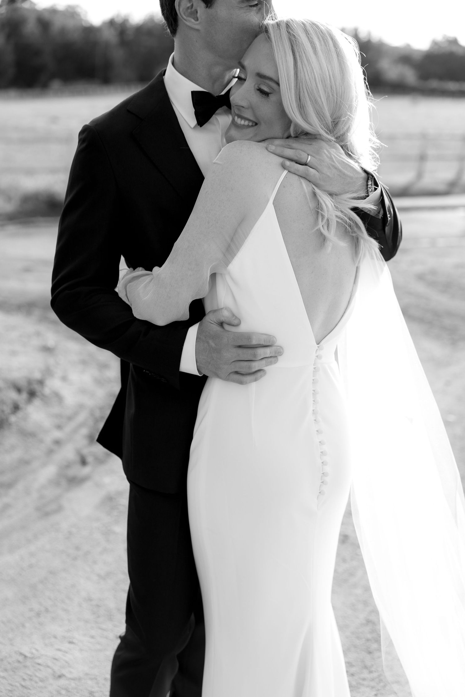 Black and white wedding portraits capturing intimate embraces between a bride and groom.