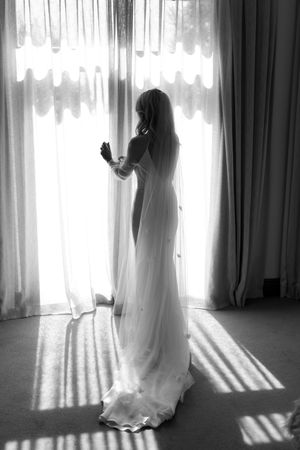Ethereal black and white series showing a figure in a flowing white dress standing by sunlit windows.