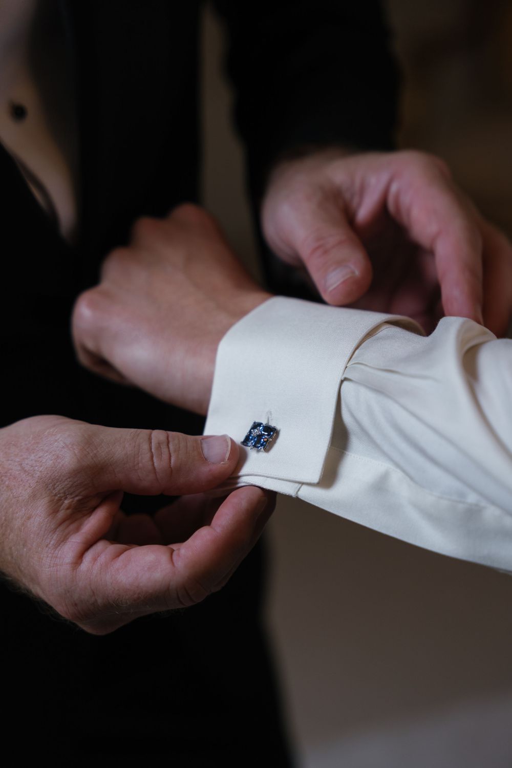 Close-up shots of hands adjusting white dress shirt cuffs and cufflinks.