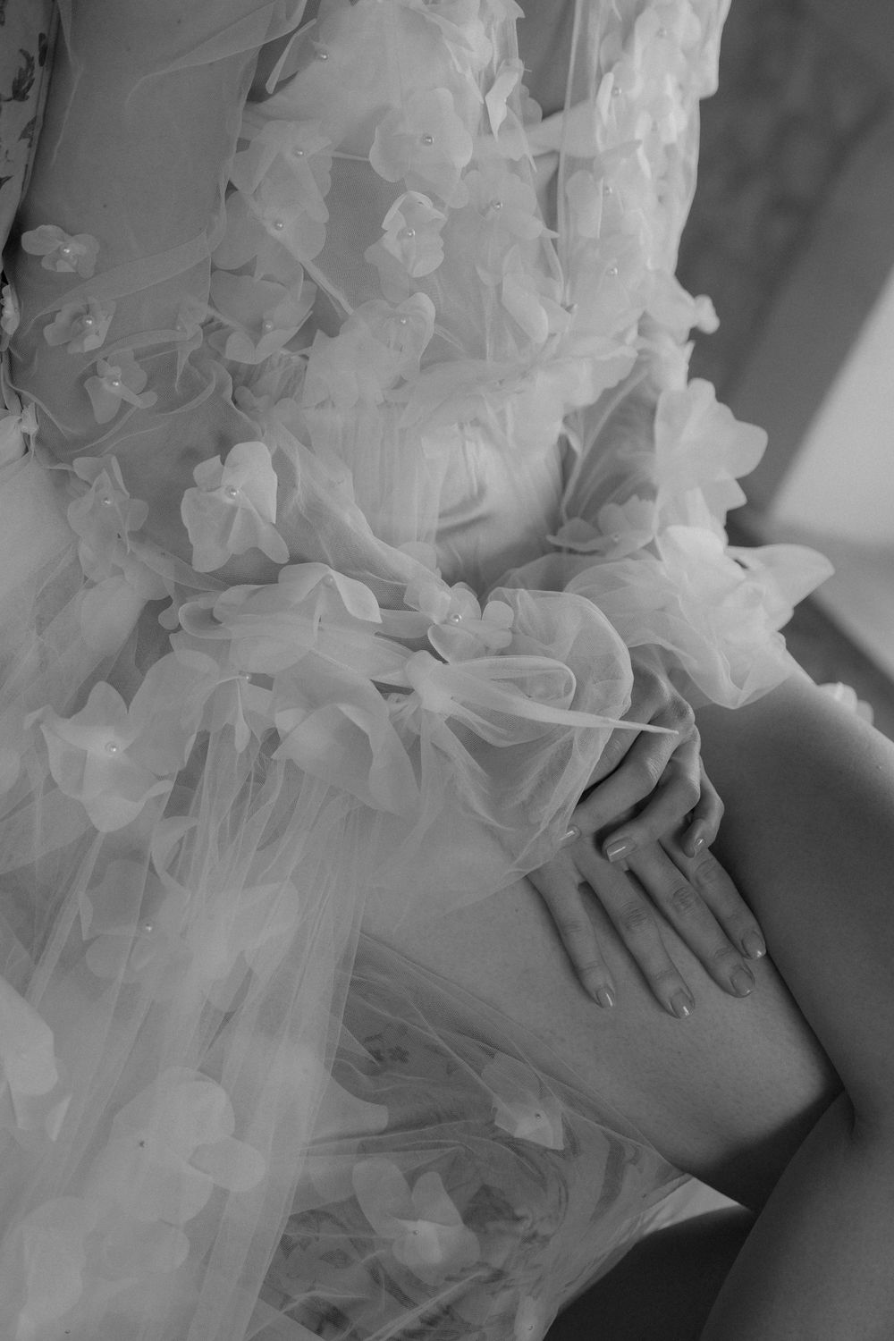 Ethereal black and white close-up of delicate white lace and tulle details on a wedding dress.