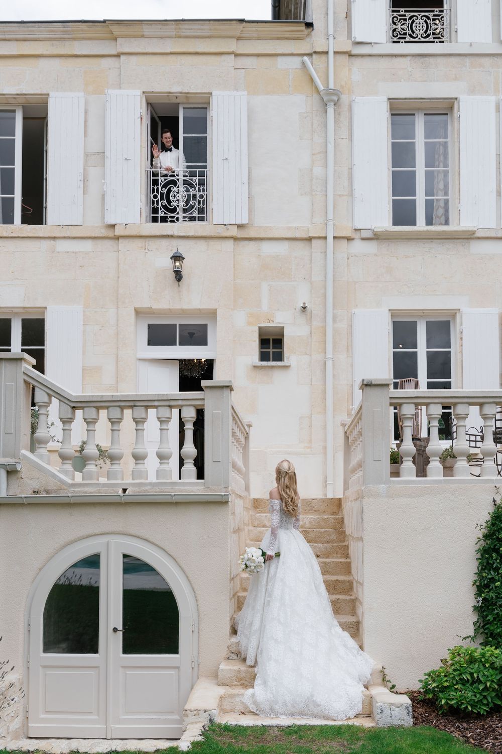 White wedding dress displayed outside a classic French-style building with stone architecture.