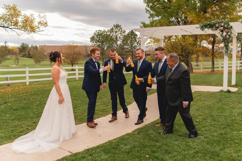 Wedding ceremony taking place outdoors on a beautiful autumn day with white fences and trees.