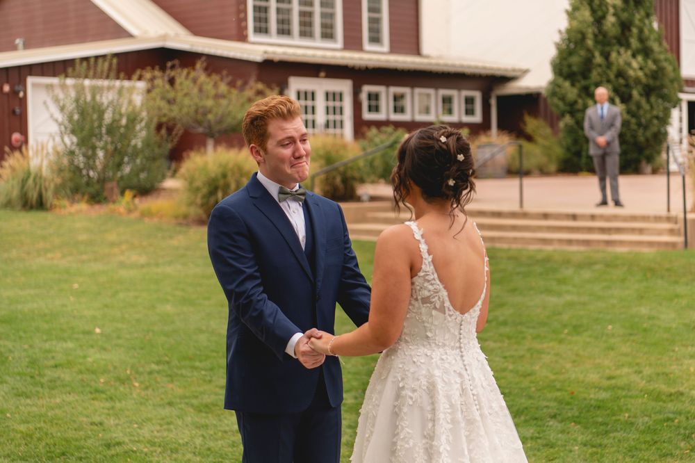 Newlywed couple shares their first dance together on a grassy lawn outside a brick building.