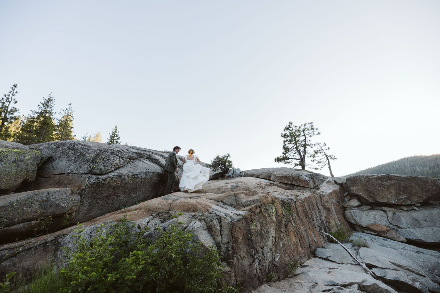 Rocky mountain overlook with granite formations and pine trees at sunset.