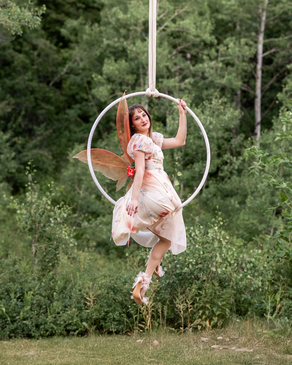 Aerialist posed on lyra hoop wearing fairy wings — fine art aerial hoop photography highlighting creative poses and form inspiration.