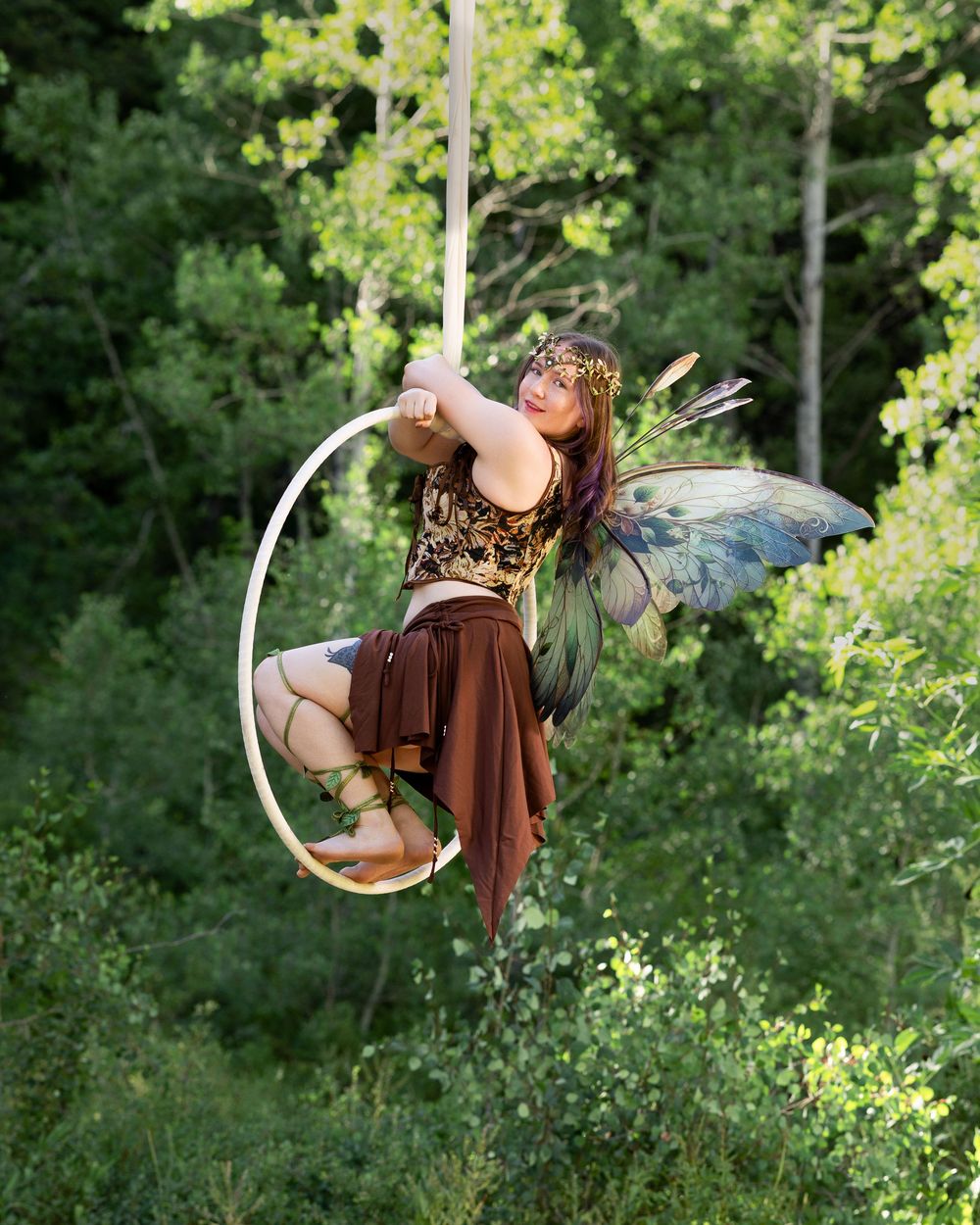 Lyra aerialist with delicate fairy wings — striking still pose captured in fine art aerial hoop photography for inspiration.