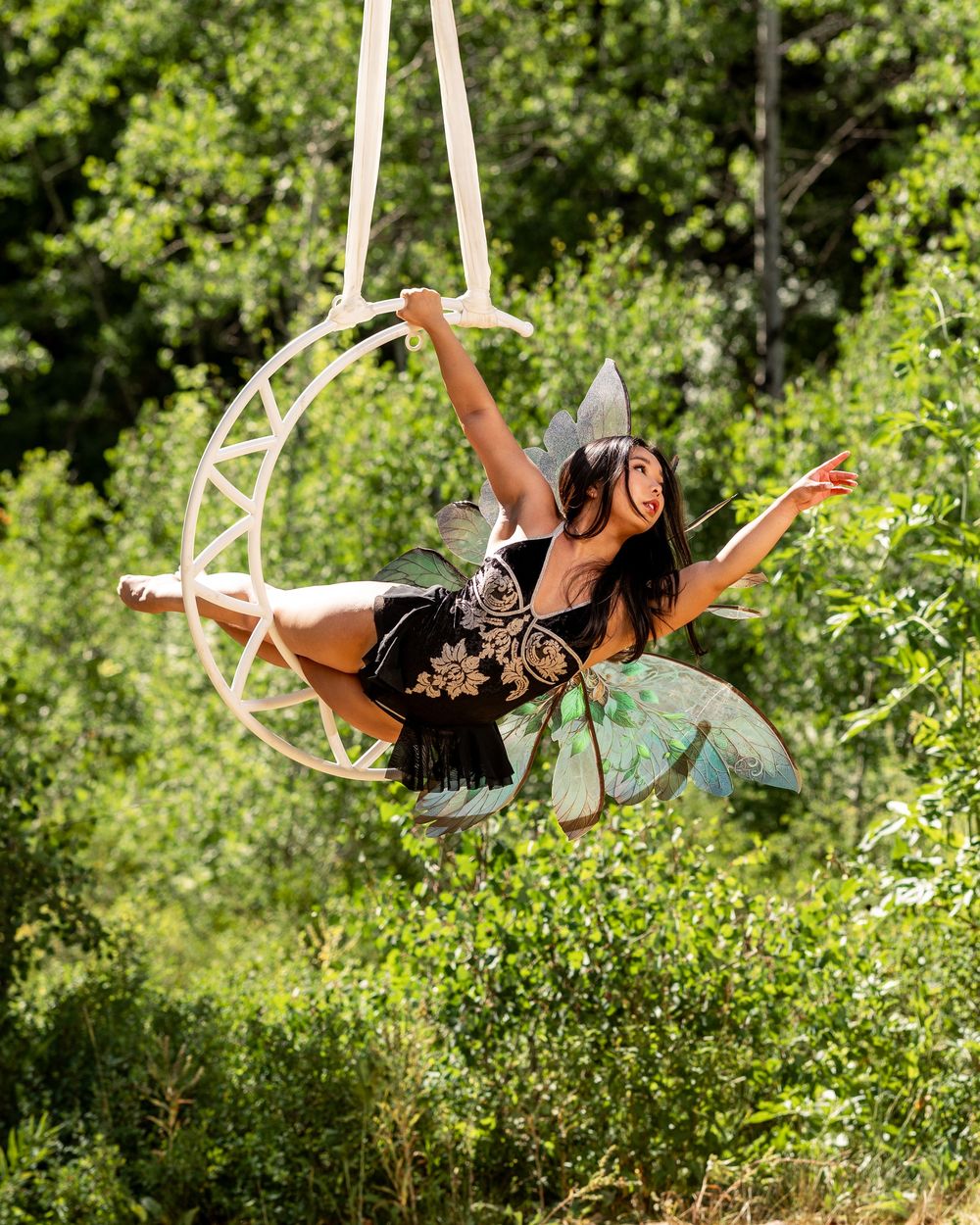 Fairy-winged aerialist on moon hoop in elegant pose — aerial hoop photography perfect for performers seeking pose ideas and styling tips.