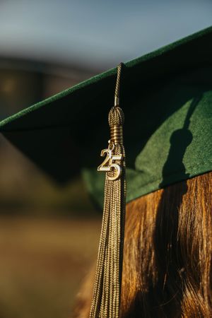 Close-up of green graduation cap tassel with gold Class of 2025 charm.