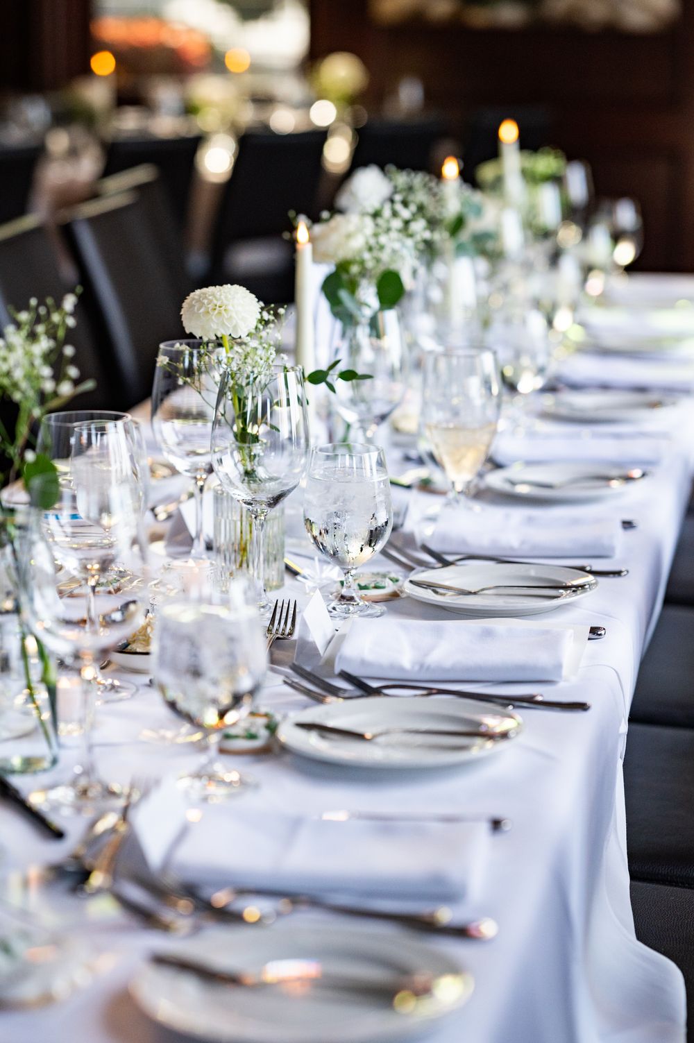 Elegant wedding reception table settings with white linens and delicate floral centerpieces.