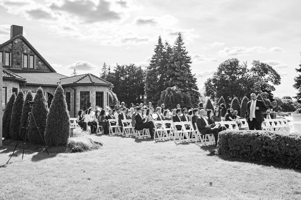 Wide panoramic view of an outdoor wedding ceremony setup with guests seated on a hillside.