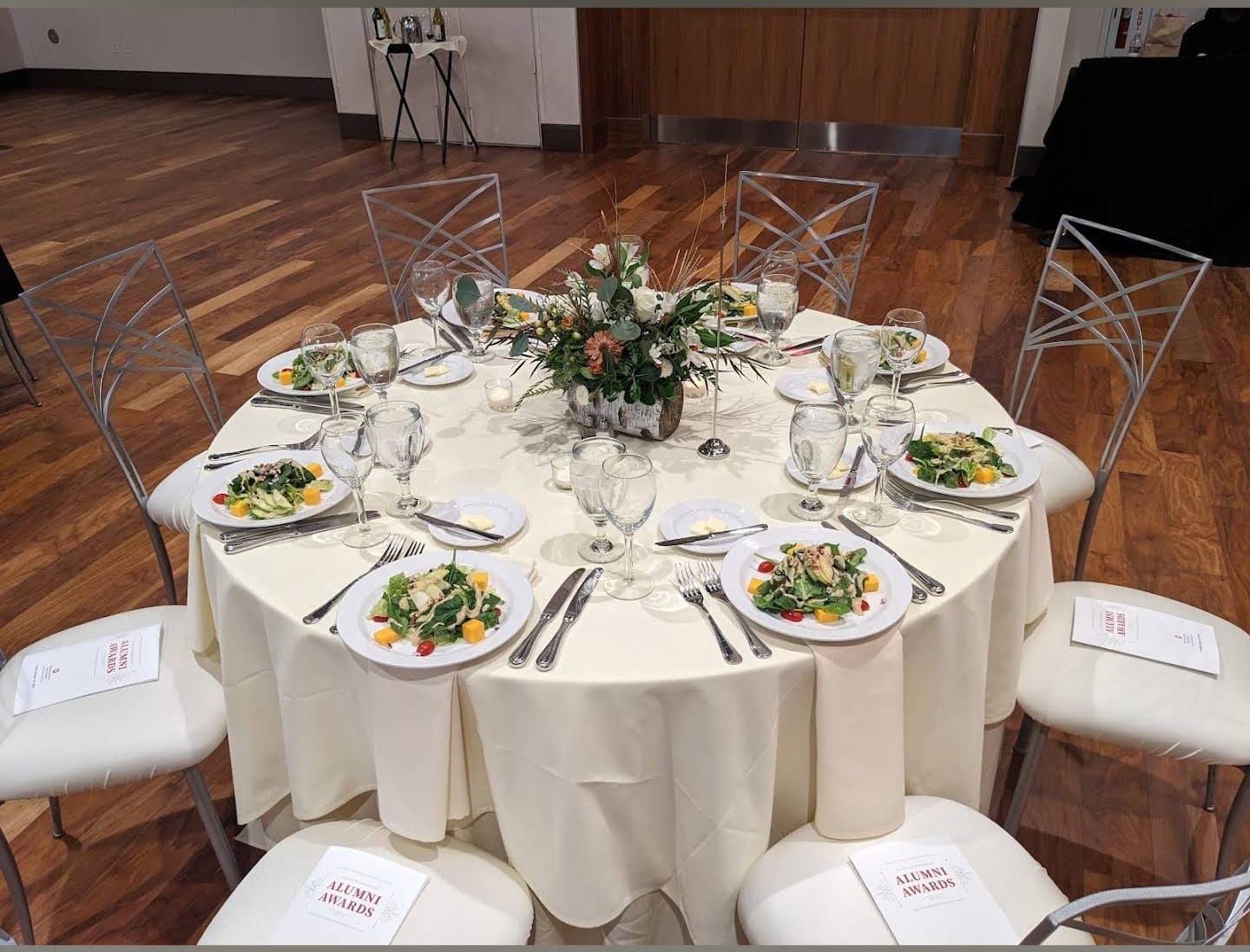 Elegant round dining tables set with white linens and floral centerpieces for a wedding reception.