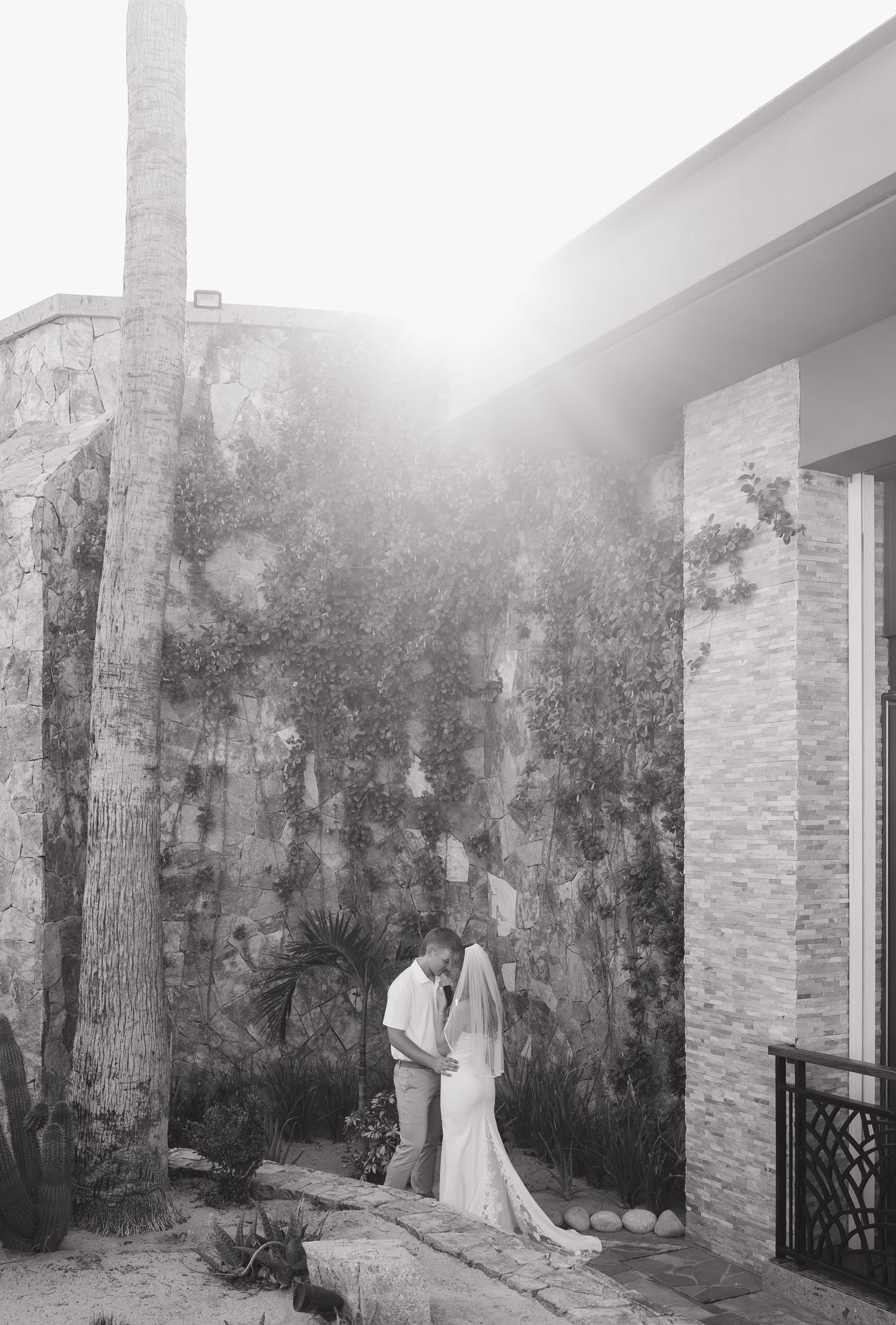 Elegant white wedding dress displayed against textured stone wall in outdoor venue setting.