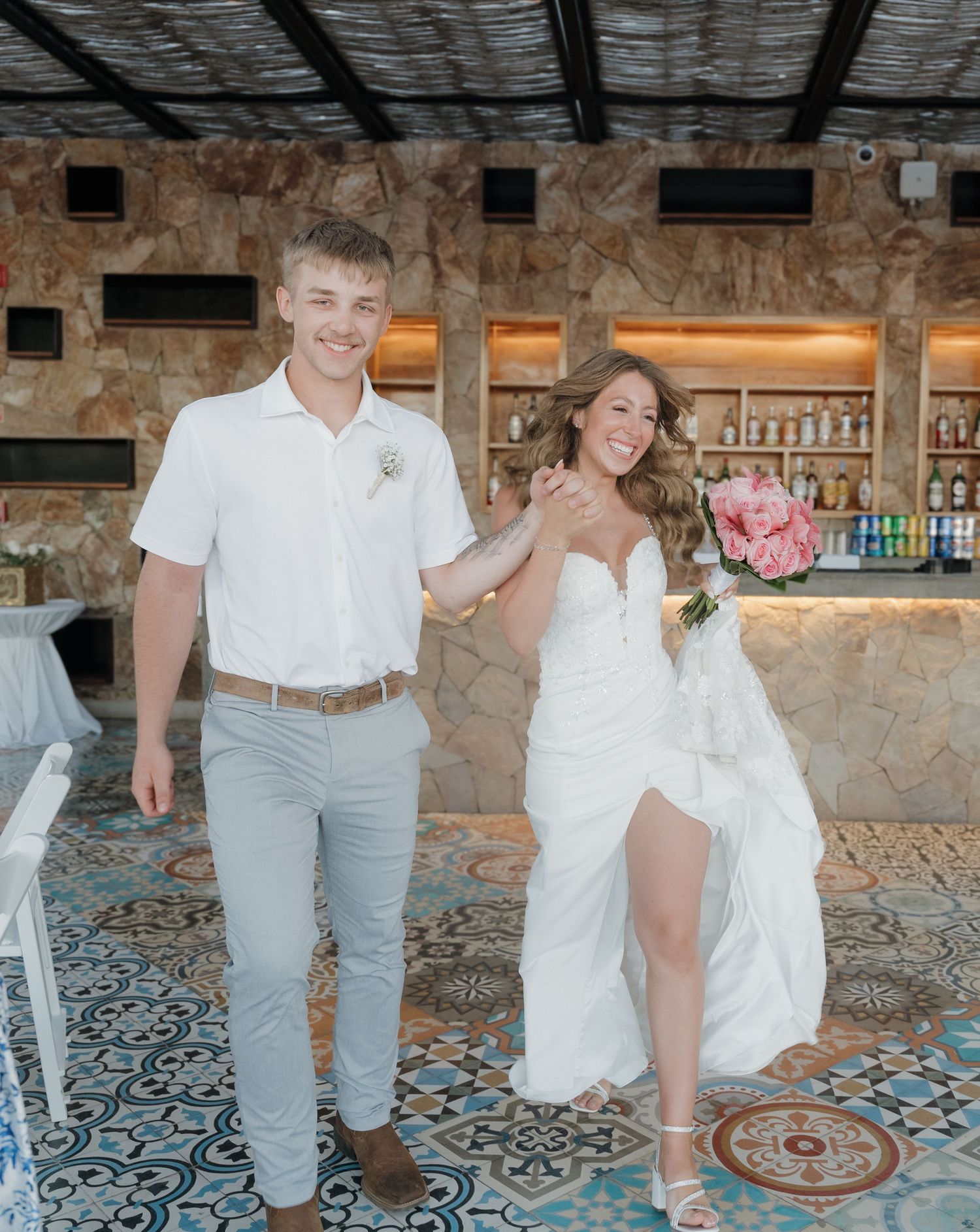 Couple celebrating at a rustic stone venue with tiled floors and decorative lighting.