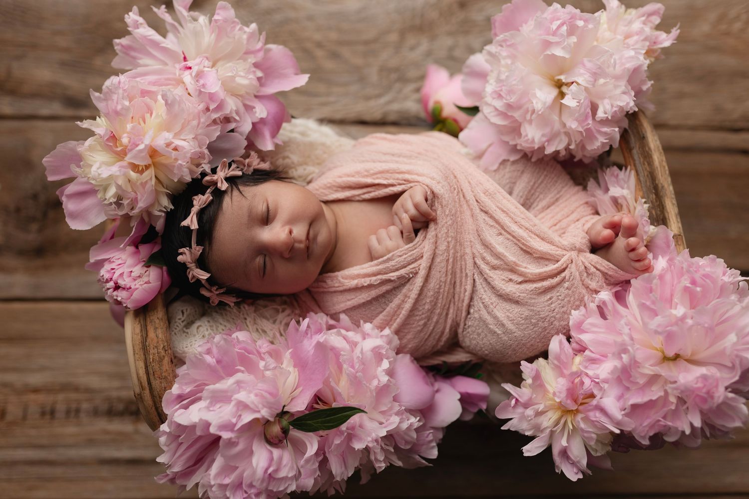 A panoramic collage of pink peonies and soft blush fabric arranged artistically on rustic wooden planks.
