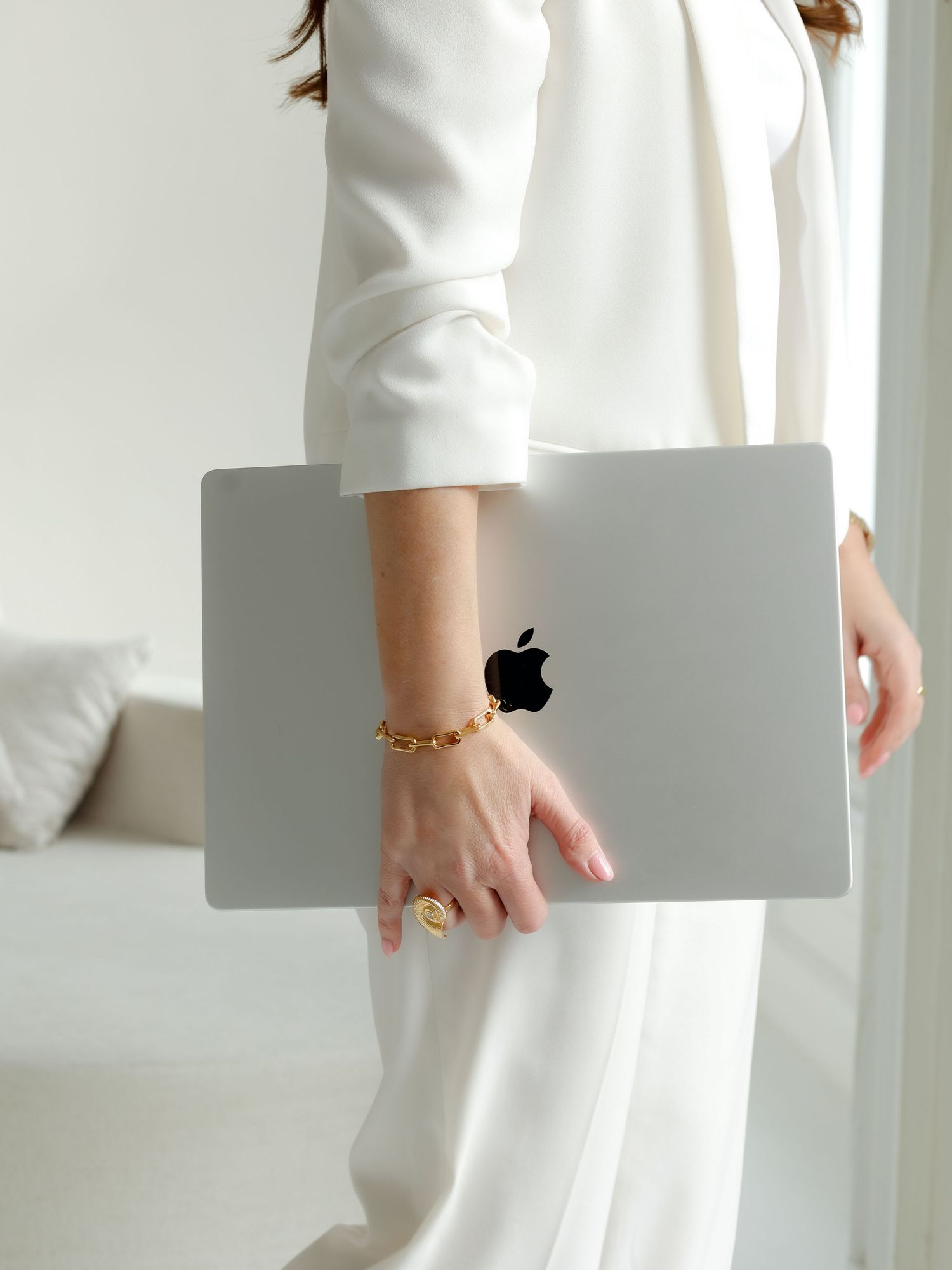 Person sitting on white couch in minimalist white room setting.