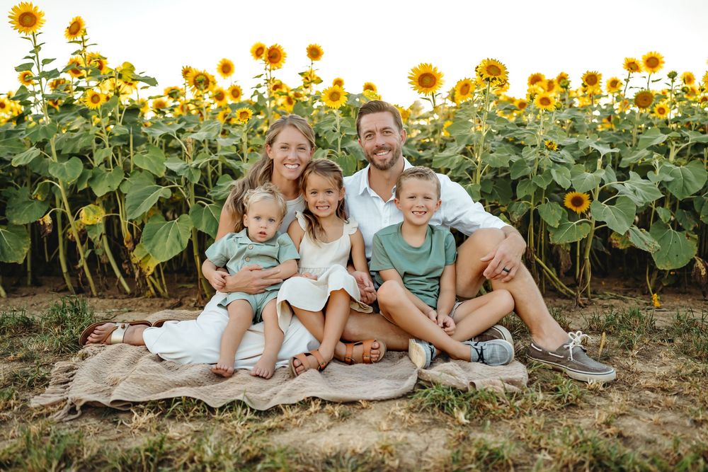 Beautiful family photo session in a blooming sunflower field during golden hour.