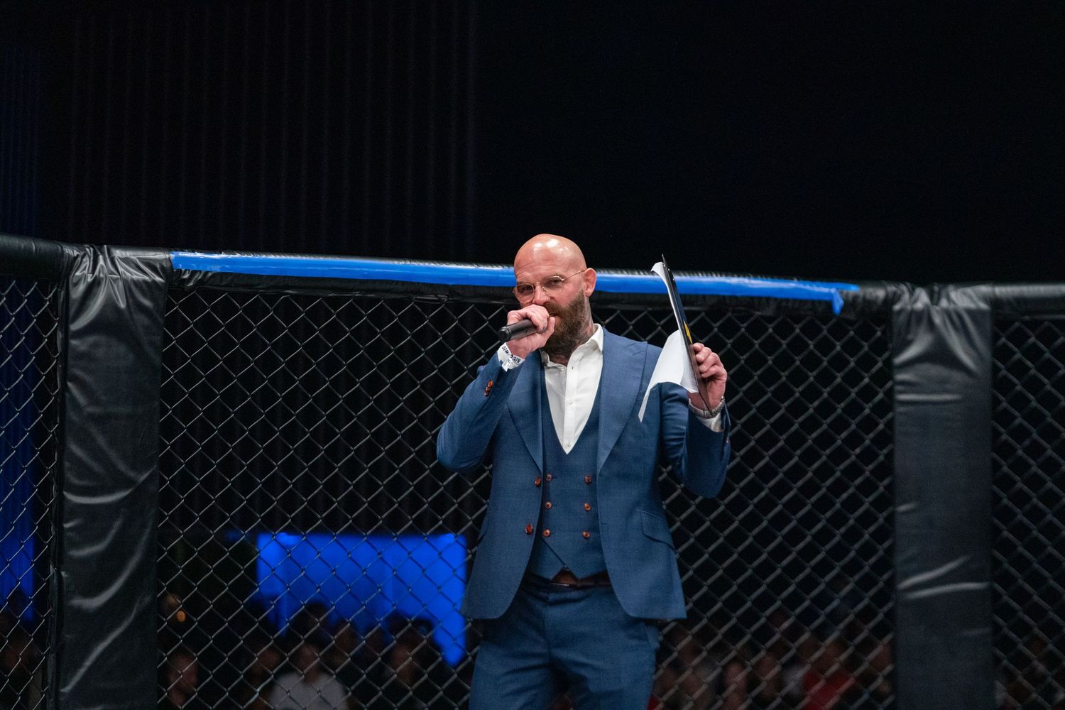 Fighter celebrates victory in octagon cage with arms raised during MMA event.